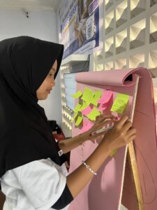 Peserta pelatihan menulis cerpen menempelkan sticky note pada papan ide cerita.